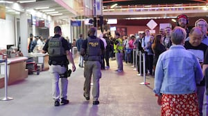 Ice agents walk through a long line of travelers at Atlanta Hartsfield-Jackson International Airport
