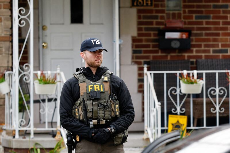 A member of the FBI Joint Terrorism Task Force stands watch in the front yard as law enforcement searches a home in Dearborn, Michigan, on October 31, 2025. FBI Director Kash Patel said Friday that the agency had thwarted a "potential terrorist attack" planned in the northern state of Michigan over Halloween weekend. Patel said the FBI arrested multiple subjects. (Photo by JEFF KOWALSKY / AFP) (Photo by JEFF KOWALSKY/AFP via Getty Images)