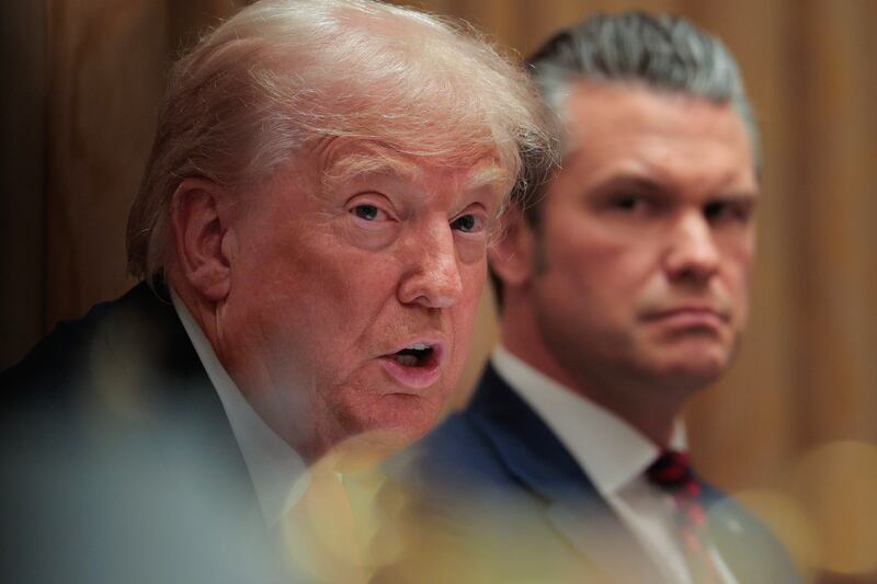 U.S. Secretary of War Pete Hegseth (R) looks on as U.S. President Donald Trump speaks