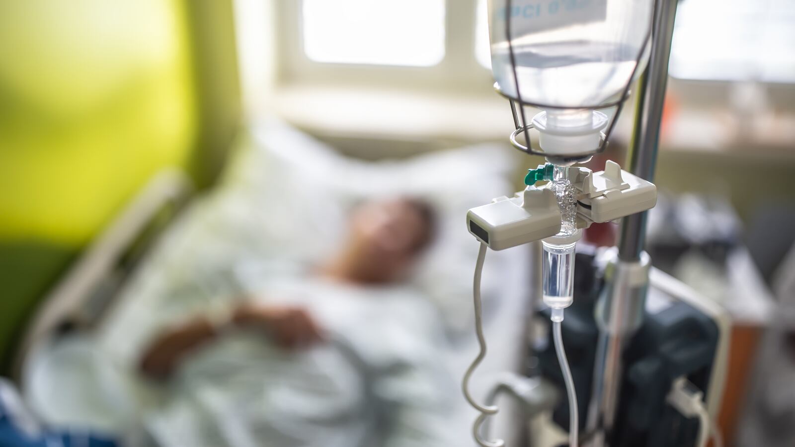 A patient receiving a drip infusion from an IV bag.