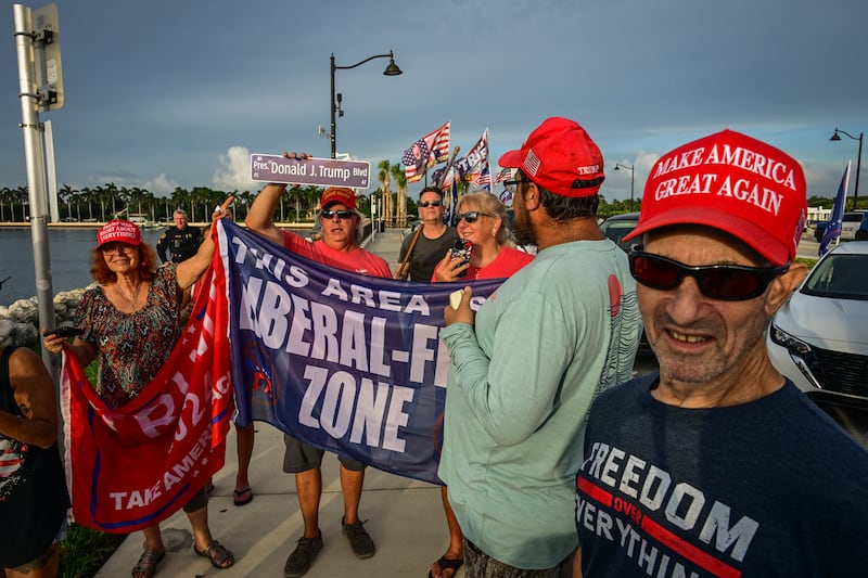 Trump supporters hold flags near the president's Mar-a-Lago residence in West Palm Beach, Florida, on July 17, 2025.
