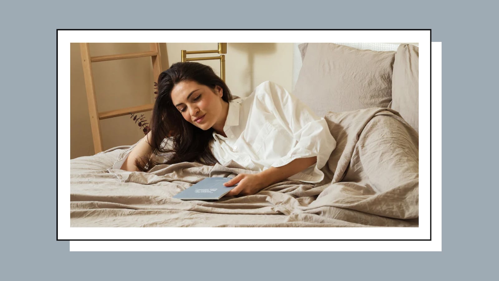 A woman lying down on a Bare Home Classic Mattress. She is wearing white clothes and is about to read a book.