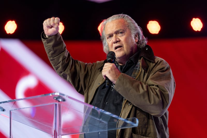 Steve Bannon, raised fist, at a podium speaking.