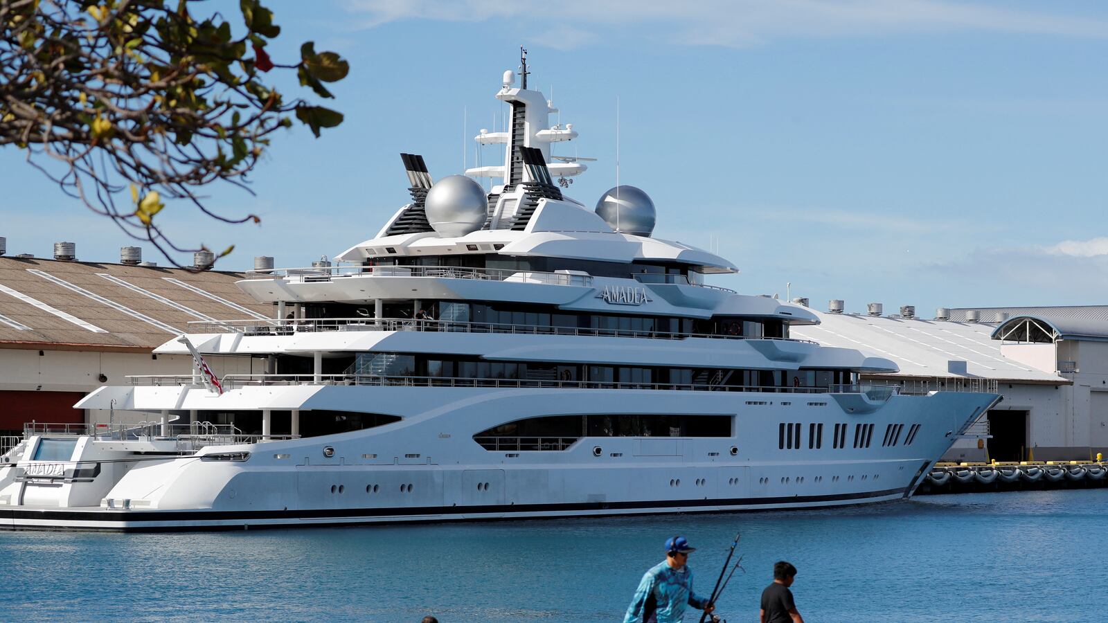 Fishermen set up their gear across the harbour from the Russian-owned super yacht Amadea