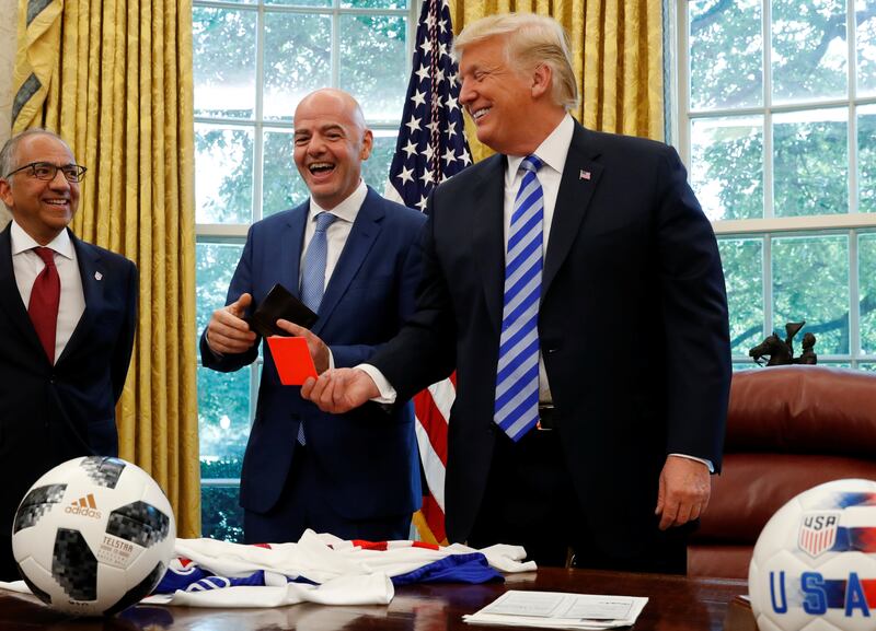 U.S. President Donald Trump holds up a red card as he meets with FIFA President Gianni Infantino in the Oval Office of the White House in Washington, U.S., August 28, 2018.