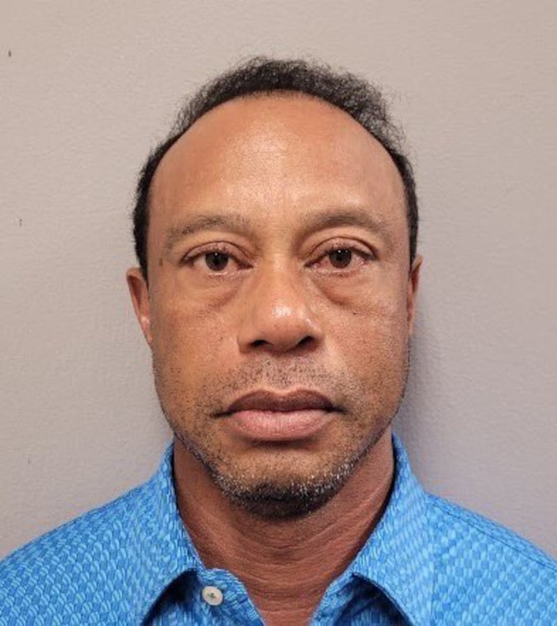 A mug shot of professional golfer Tiger Woods in a cobalt blue shirt.