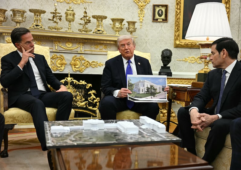US President Donald Trump shows a rendition of the East Wing of the White House currently being demolished to build a ballroom as he meets with NATO Secretary General Mark Rutte in the Oval Office of the White House in Washington, DC, on October 22, 2025. (Photo by Jim WATSON / AFP) (Photo by JIM WATSON/AFP via Getty Images)