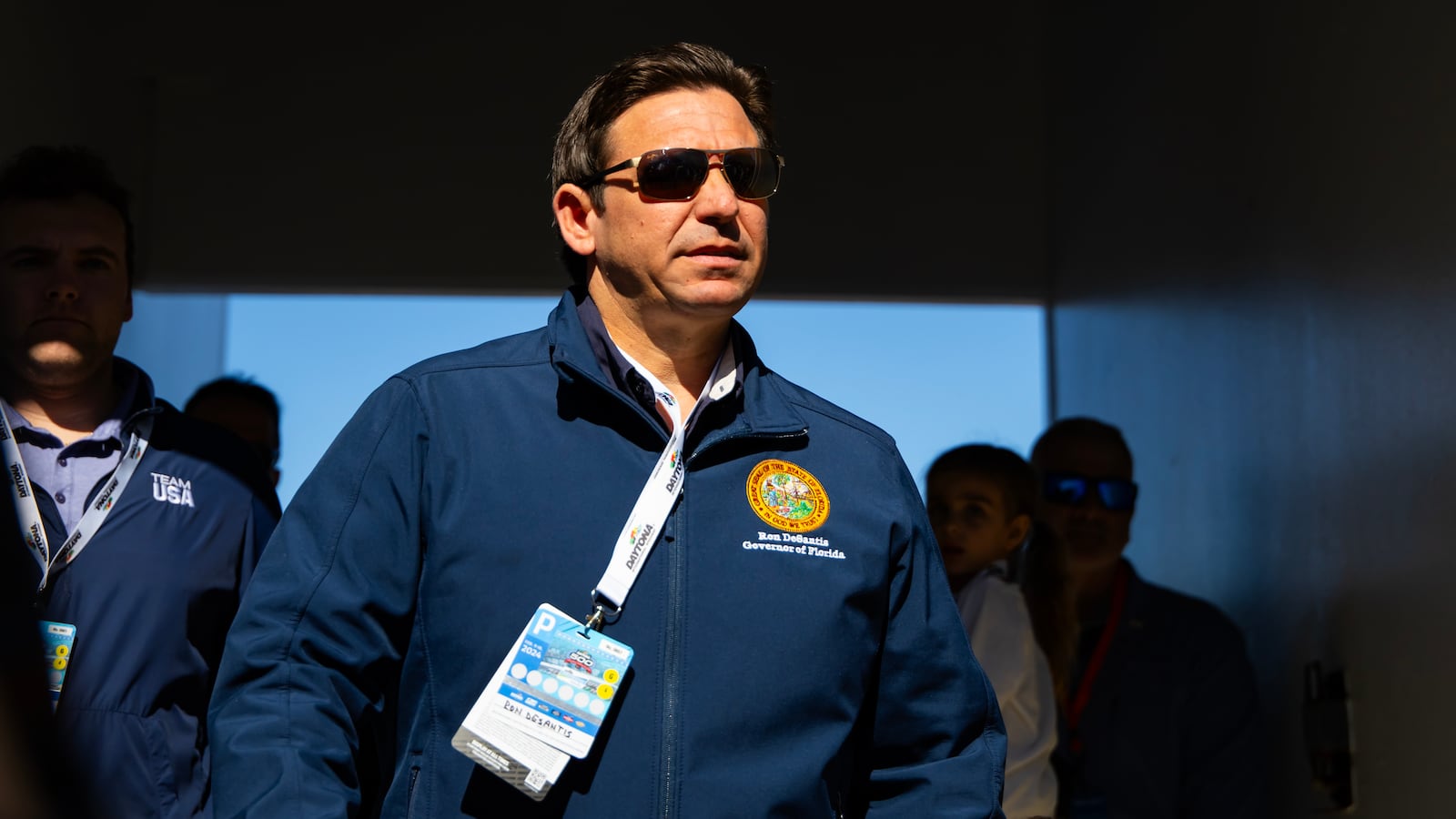 Florida Gov. Ron DeSantis walks into the Daytona 500 with a lanyard around his neck.