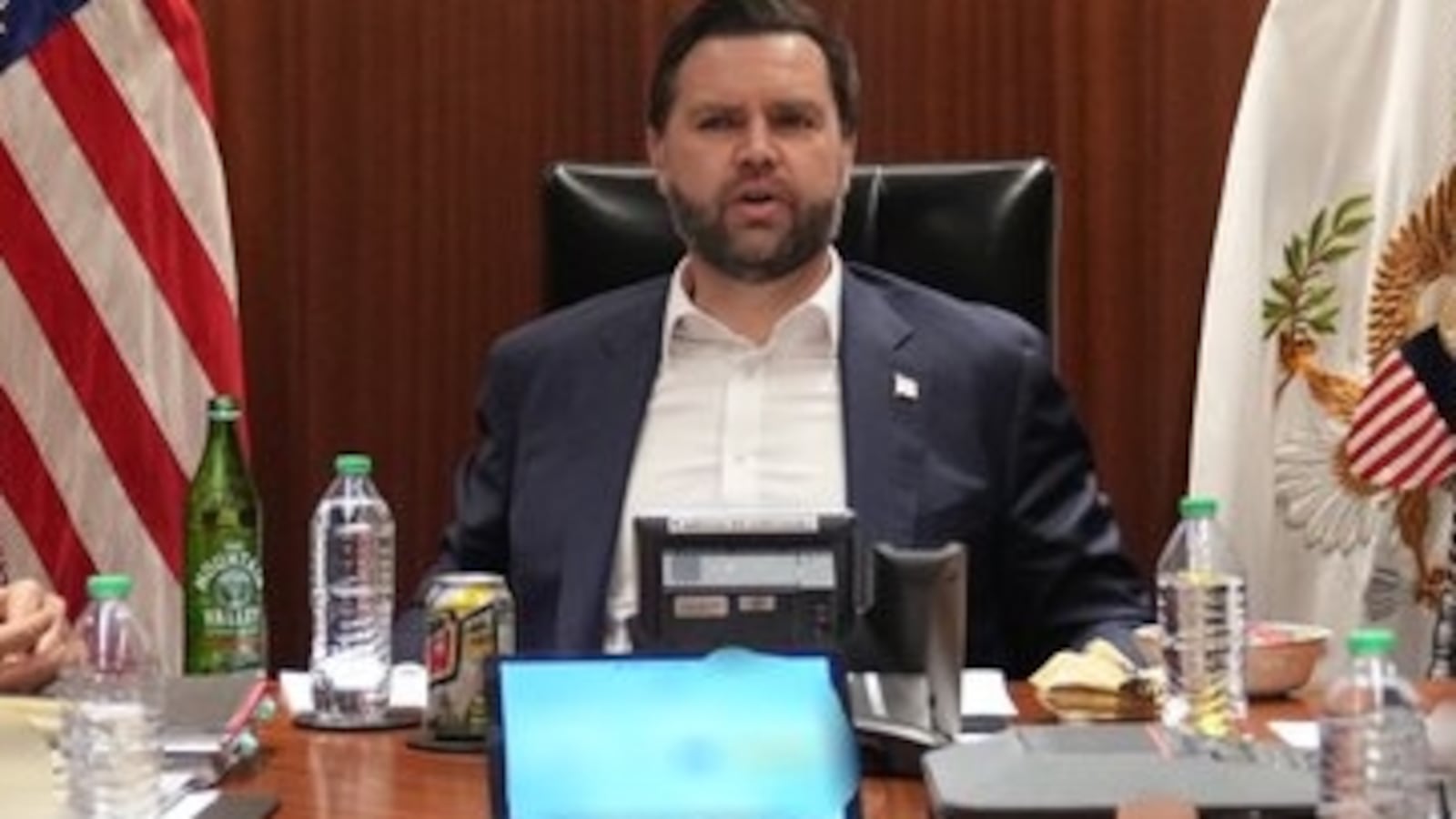JD Vance sitting at the head of a table in a wood-lined room with his seal and Tulsi Gabbard and Scott Bessent.