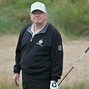 US President Donald Trump reacts after playing from the first tee to officially open the Trump International Golf Links course