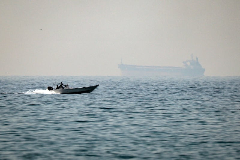 TOPSHOT - A motorboat cruises along the shore off the town of Al Jeer on the Strait of Hormuz in the northern emirate of Ras Al Khaimah, with a tanker seen in the background, on February 25, 2026. (Photo by FADEL SENNA / AFP via Getty Images)
