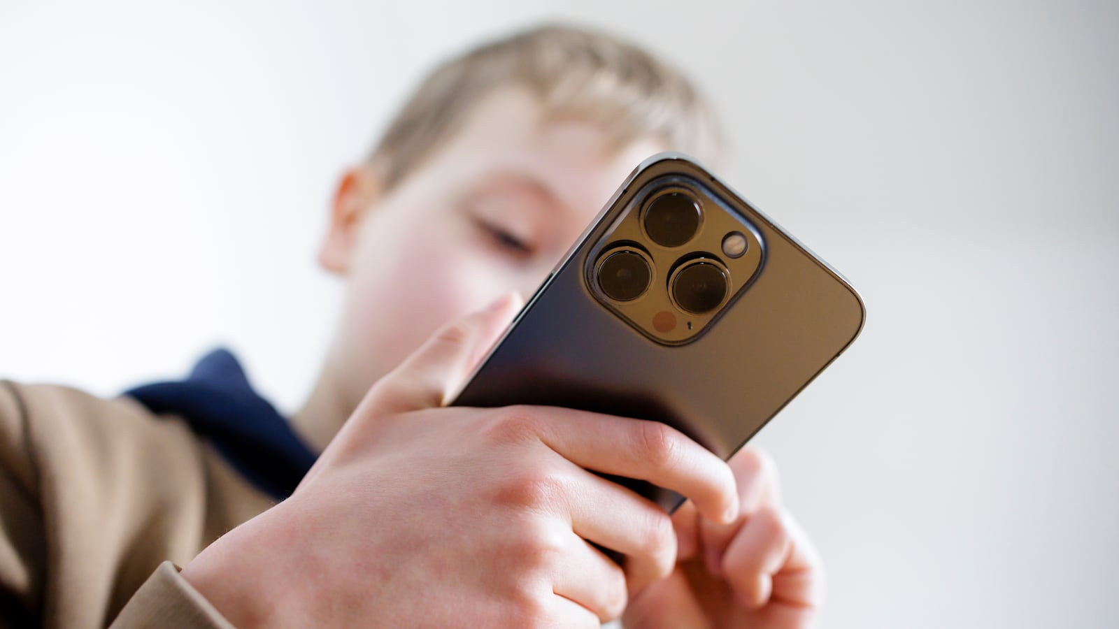 BERLIN, GERMANY - MARCH 11: Symbolic photo on the topic of mobile phone use by children. A boy holds a smartphone in his hand on March 11, 2025 in Berlin, Germany. (Photo Illustration by Thomas Trutschel/Photothek via Getty Images)