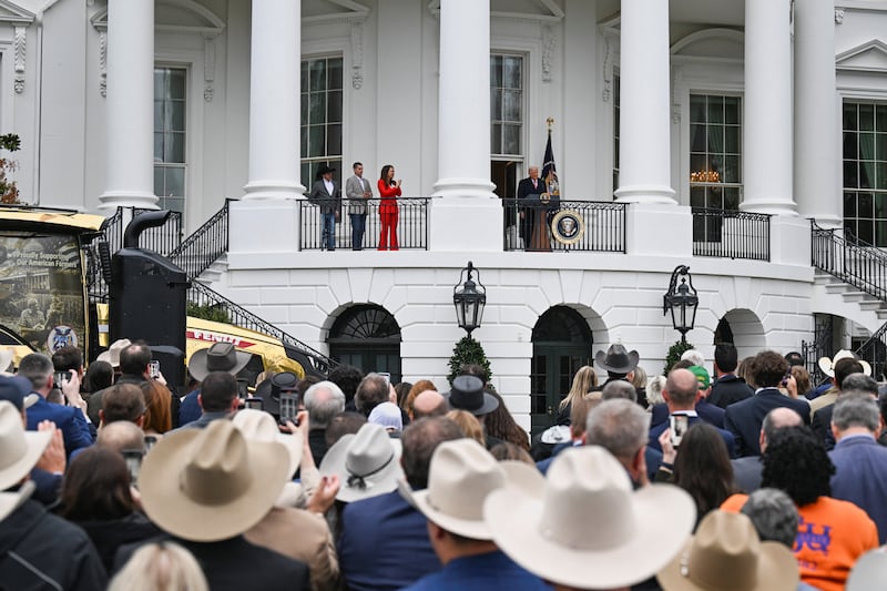 President Donald Trump steps onto a balcony to give remarks to farmers on the South Lawn of the White House in Washington, D.C., U.S., March 27, 2026 with the gold tractor below.