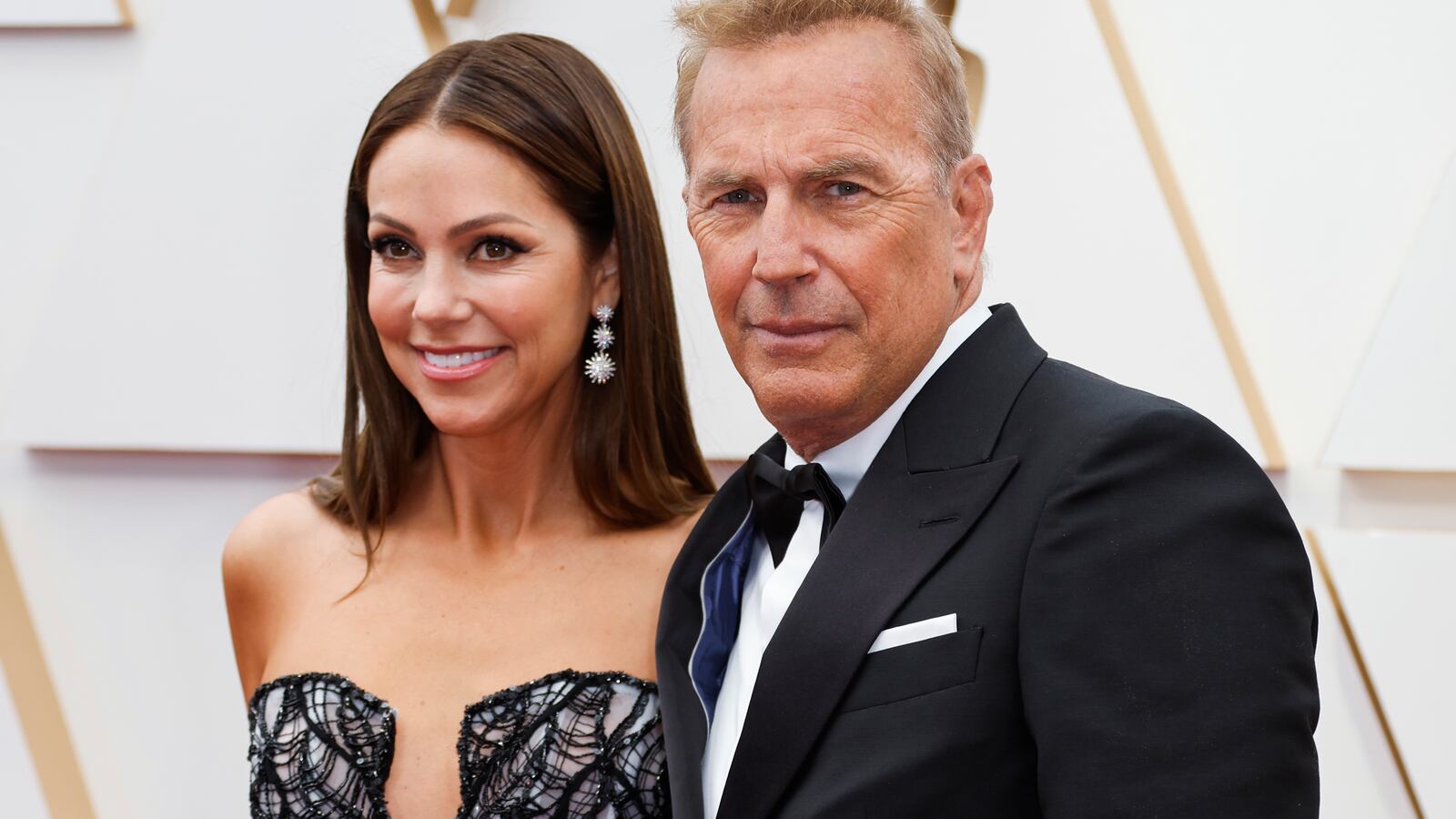 Kevin Costner and wife Christine Baumgartner pose on the red carpet during the Oscars arrivals at the 94th Academy Awards.