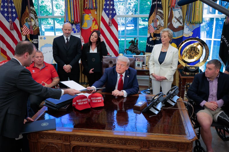 White House staff secretary Will Scharf (L) hands U.S. President Donald Trump (C) an executive order to sign as Secretary of Commerce Howard Lutnick, Secretary of Labor Lori Chavez-DeRemer and Secretary of Education Linda McMahon look on in the Oval Office at the White House on April 23, 2025 in Washington, DC.