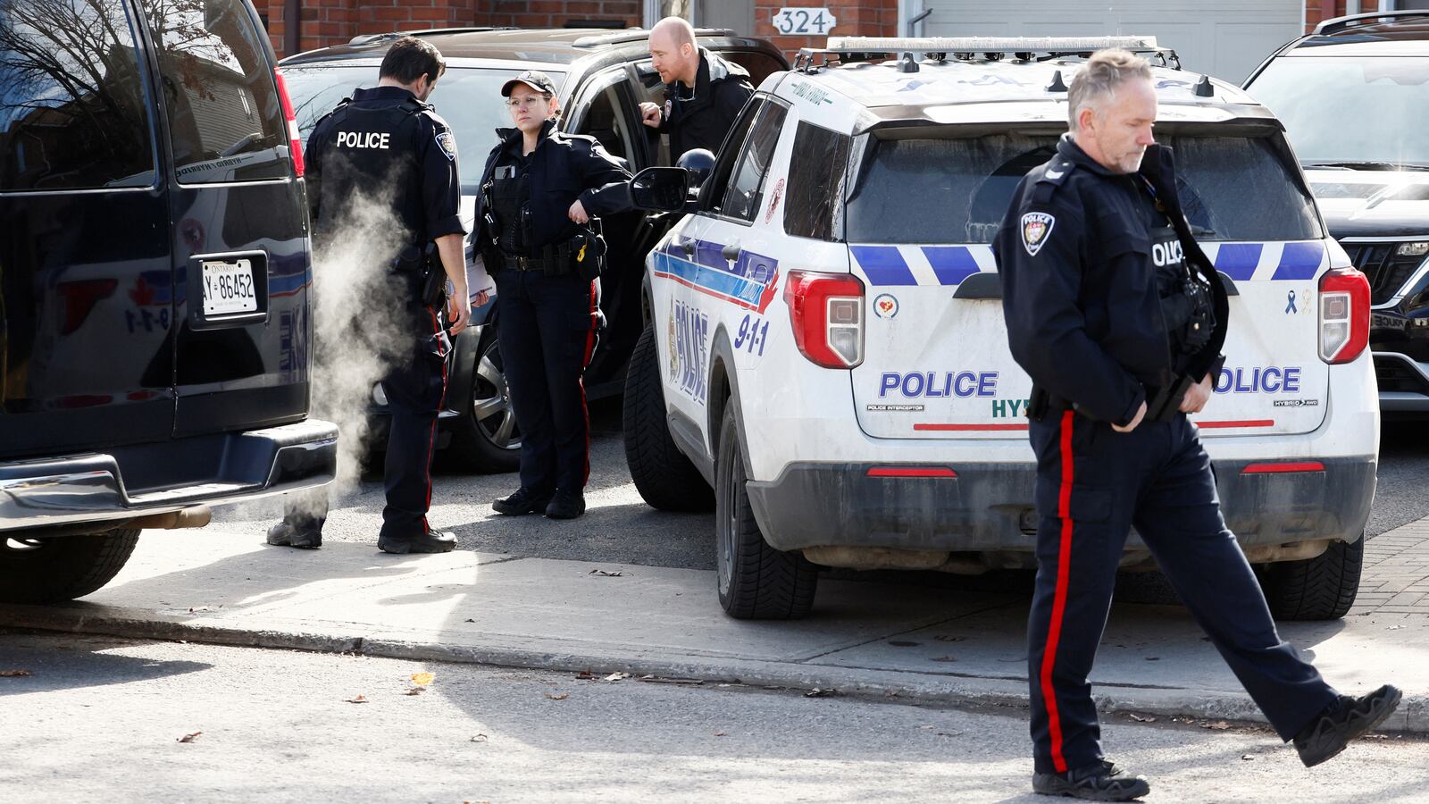 Police officers chat and walk outside the scene where six people were killed in a mass shooting.