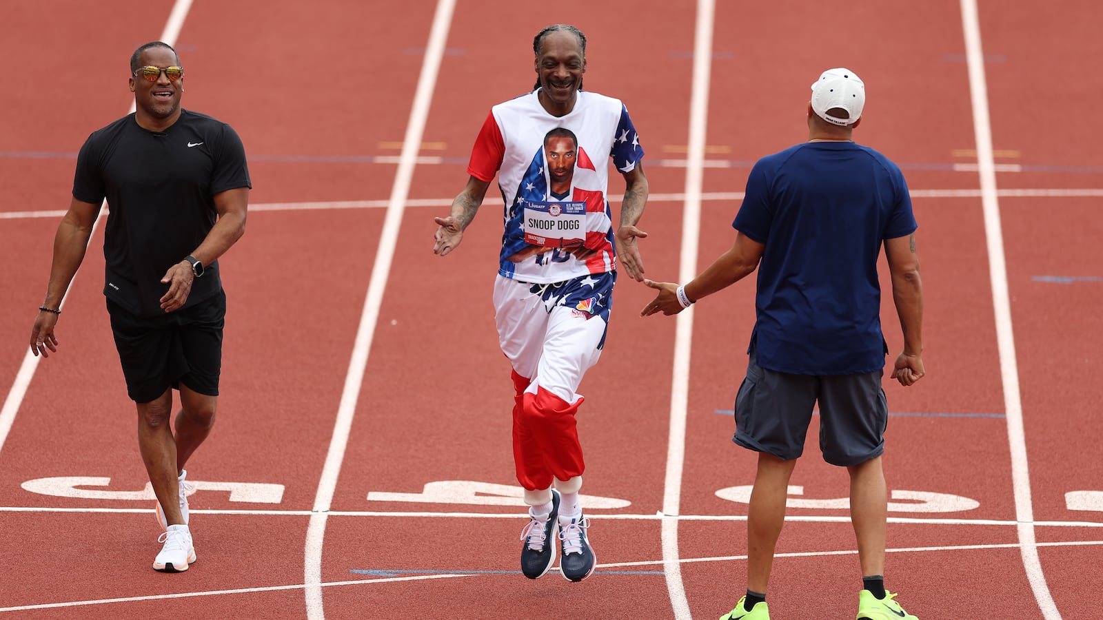 Wallace Spearmon, Snoop Dogg and Ato Boldon high-five after running on the track on during U.S. 2024 Olympic trials.