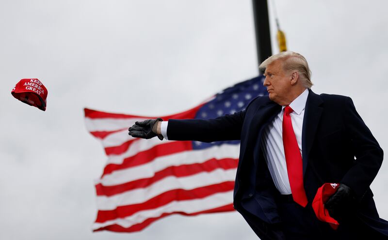U.S. President Donald Trump tosses out Make America Great Again (MAGA) caps as he arrives for a campaign rally at Oakland County International Airport in Waterford Township, Michigan, U.S., October 30, 2020. REUTERS/Carlos Barria