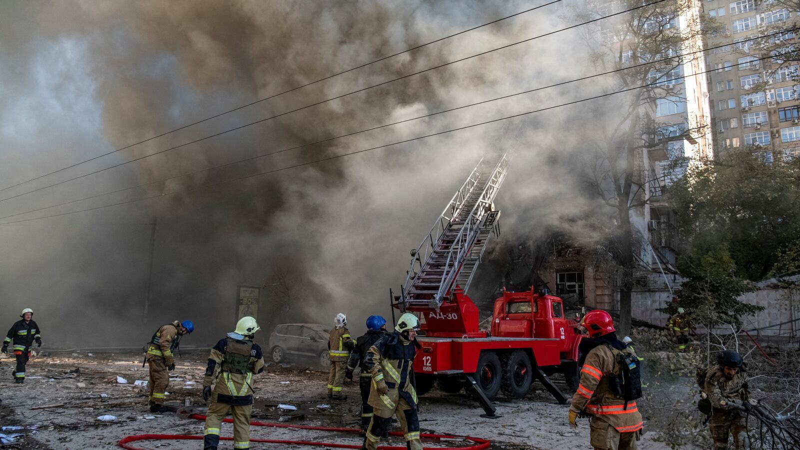 Firefighters help a local woman evacuate from a residential building destroyed by a Russian drone strike in Kyiv, Ukraine, Oct. 17, 2022.