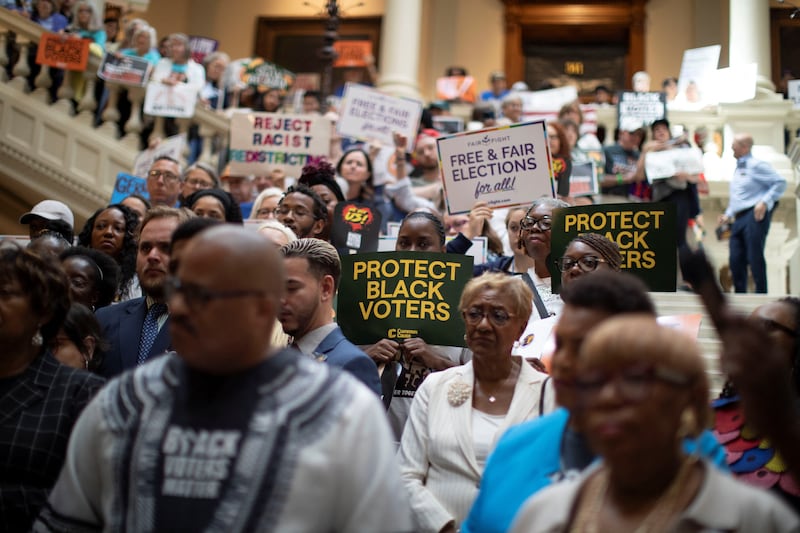 People holding signs protest during a press conference at the Georgia State Capitol building, as the Georgia Assembly prepares to hold a special session on voter redistricting, in Atlanta, Georgia, U.S. June 17, 2026.  REUTERS/Alyssa Pointer