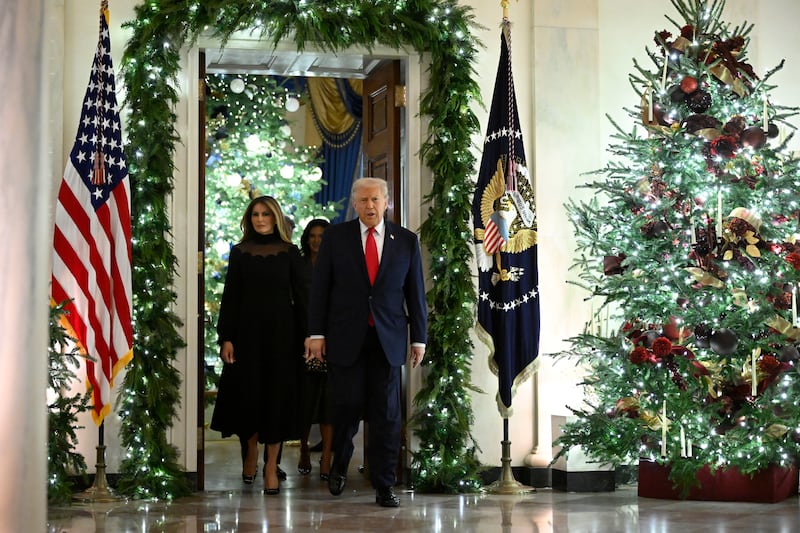 President Donald Trump and first lady Melania walk among Christmas decorations en route to the East Room at the White House on December 5, 2025 in Washington, DC.