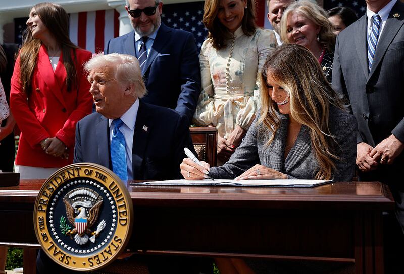 Melania Trump signs the  TAKE IT DOWN Act alongside U.S. President Donald Trump, lawmakers and victims of AI deepfakes and revenge porn, during a signing ceremony in the Rose Garden of the White House on May 19, 2025 in Washington, DC. The first lady made the Tools to Address Known Exploitation by Immobilizing Technological Deepfakes on Websites and Networks (TAKE IT DOWN) Act a priority, traveling to Capitol Hill to lobby lawmakers and show her support for the legislation, which addresses non-consensual intimate imagery, or "revenge porn," and artificial intelligence deepfakes posted online and to social media. (Photo by Chip Somodevilla/Getty Images)