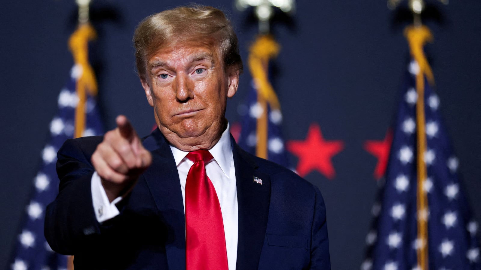 Donald Trump makes a face and points while on stage at a campaign event.