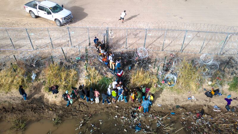 In an aerial view, immigrants pass through coils of razor wire while crossing the U.S.-Mexico border on March 13, 2024 in El Paso, Texas.