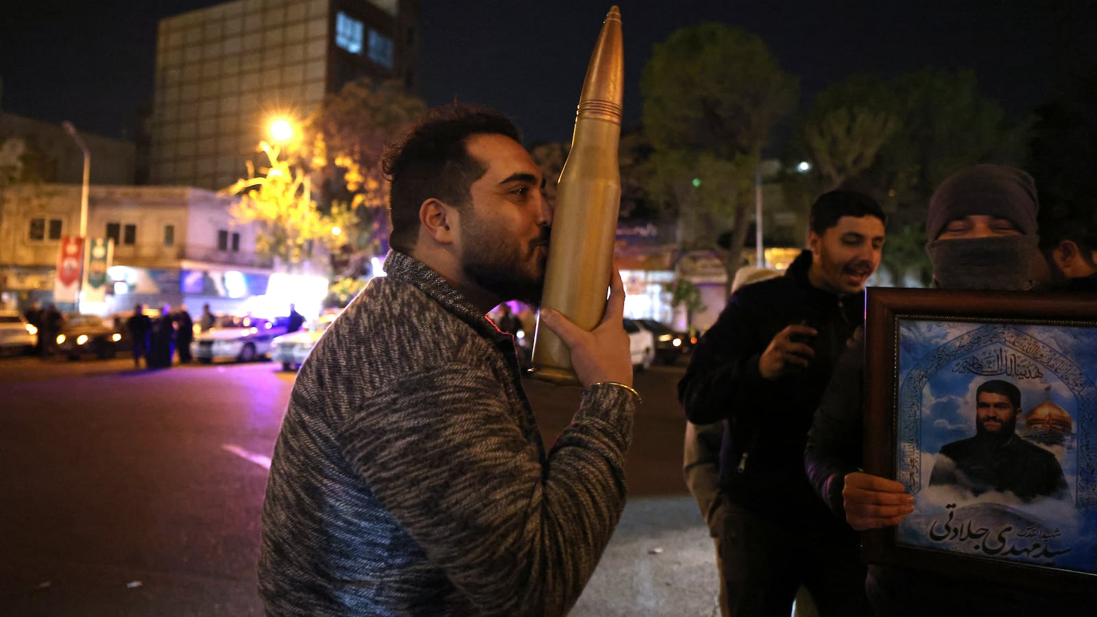 A demonstrator kisses a bullet shell replica as others gather at Palestine Square in Tehran on April 14, 2024, after Iran launched a drone and missile attack on Israel.