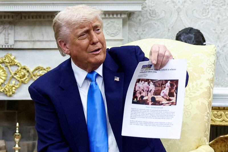President Donald Trump shows a copy of an image that he falsely claimed shows white farmers killed in South Africa.
