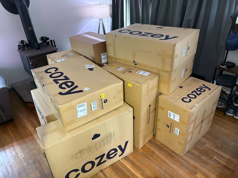 Thirteen Cozey boxes piled up in a living room.