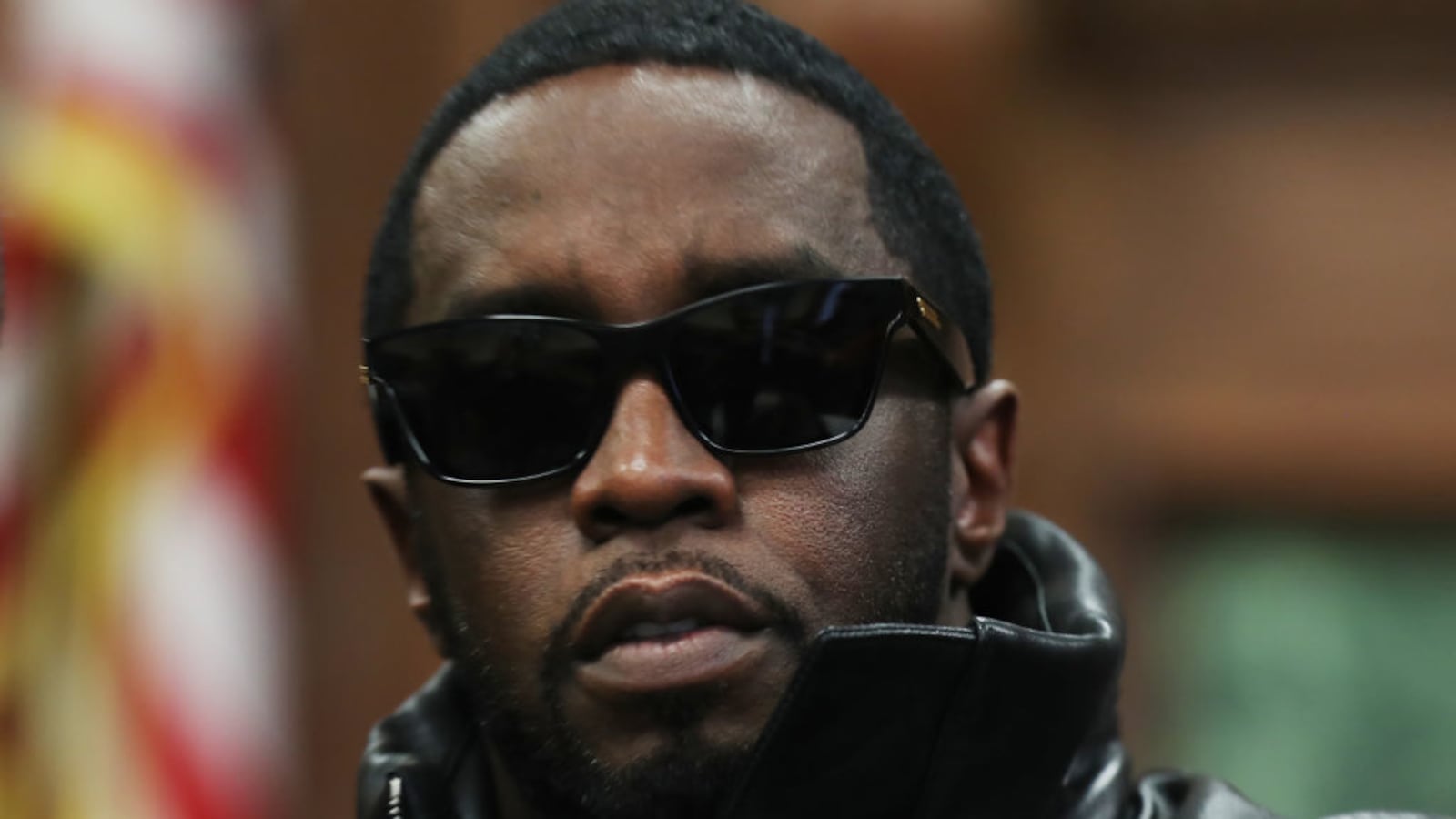 Sean Combs, wearing sunglasses, sits in a courtroom.