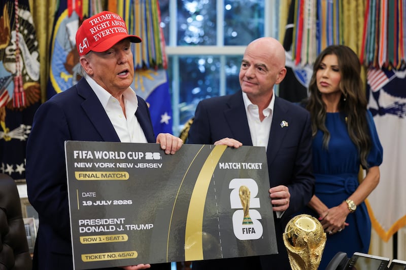 U.S. President Donald Trump and FIFA president Gianni Infantino hold a 2026 FIFA World Cup final match ticket that was presented to President Trump, as the President makes an announcement on the 2026 FIFA World Cup, while U.S. Homeland Security Secretary Kristi Noem stands, in the Oval Office at the White House in Washington, D.C., U.S., August 22, 2025.