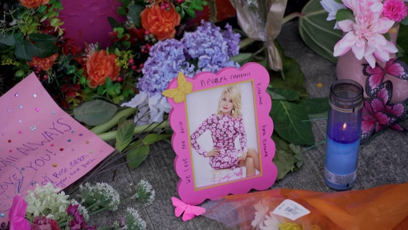 Flowers and signs are left in front of a mural of Dolly Parton in Ringgold, where the country music star married Carl Dean, in Georgia, U.S., August 26, 2026, in this screen grab taken from a video. REUTERS/Jayla Whitfield-Anderson