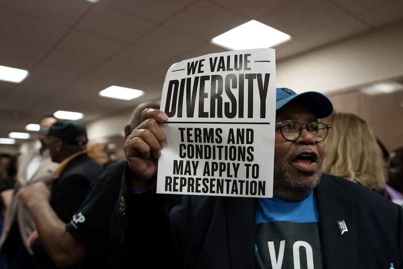 A man holds a sign in front of the hearing room, during a public hearing on redistricting as Louisiana Republicans pursue a new congressional voting map ahead of the November midterm elections, in Baton Rouge, Louisiana, U.S., May 8, 2026.