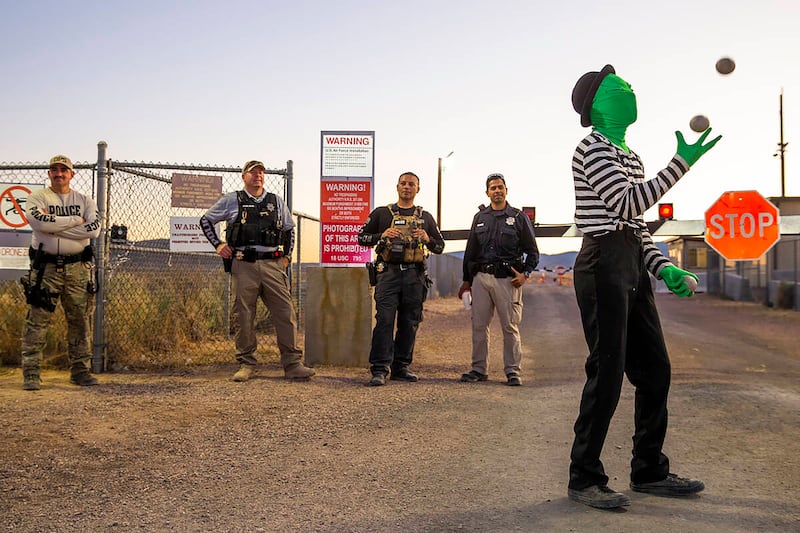 A man performing as an alien juggling mime entertains the security personnel at the back gate of Area 51 during the Alienstock festival on Saturday, Sept. 21, 2019, in Rachel, Nevada.