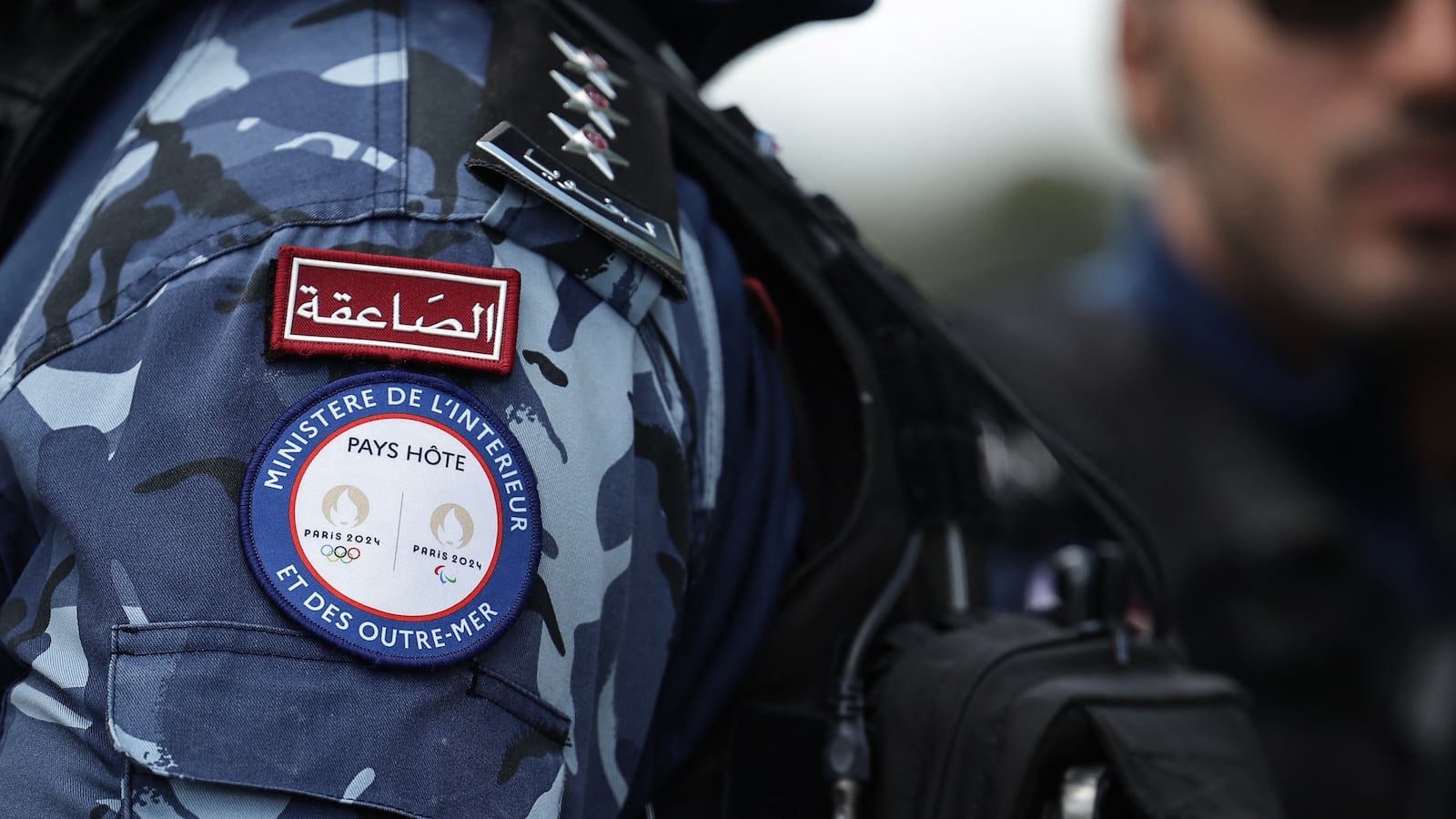 A Qatari Lekhwiya force officer wears an embroidered badge of France's Ministry for Interior and Overseas bearing the Paris 2024 Olympic and Paralypic Games logos during a patrol in Paris, on August 8, 2024, during the Paris 2024 Olympic and Paralympic Games. The grey camouflaged light armoured vehicles of the Qatari police did not go unnoticed in the streets of Paris: the foreign reinforcements have been called to help France provide security during the Olympic and Paralympic Games. (Photo by Valentine CHAPUIS / AFP) (Photo by VALENTINE CHAPUIS/AFP via Getty Images)