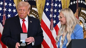 President Donald Trump reacts after bobsledder Kaillie Humphries awarded him with an Ikkos award during a Women's History Month event in the East Room of the White House in Washington, DC, on March 12, 2026.