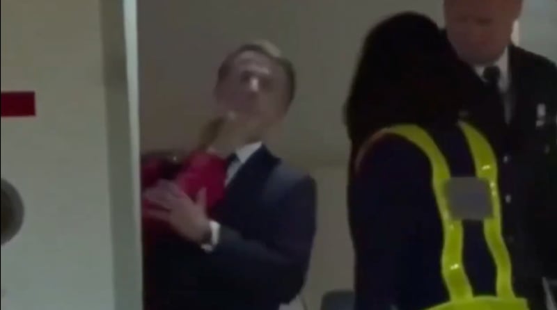 Emmanuel macron in the door of a plane with a hand hitting his face