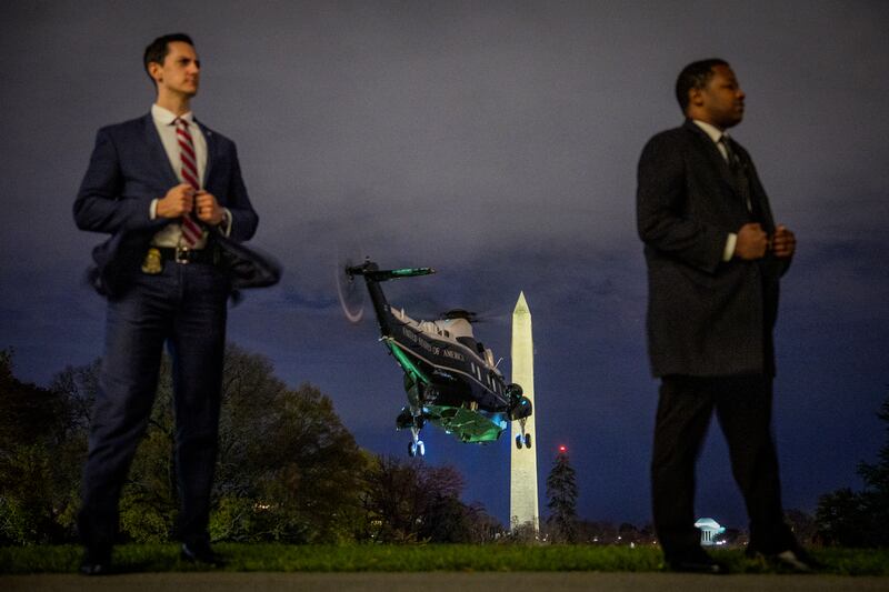 two secret service agents standing in front of marine one taking off