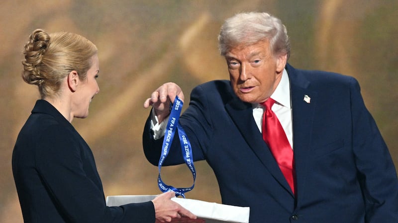 (L-R) US President Donald Trump holds a medal as he receives the FIFA Peace Prize from Italian Fifa President Gianni Infantino (out of frame) during the draw for the 2026 FIFA Football World Cup taking place in the US, Canada and Mexico, at the Kennedy Center, in Washington, DC, on December 5, 2025. (Photo by Jim WATSON / AFP via Getty Images)