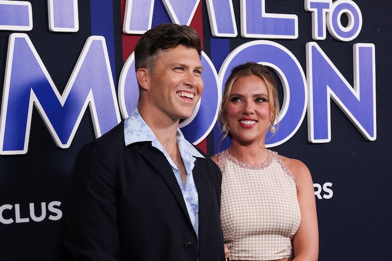 Colin Jost and Scarlett Johansson smiling at a film premiere.