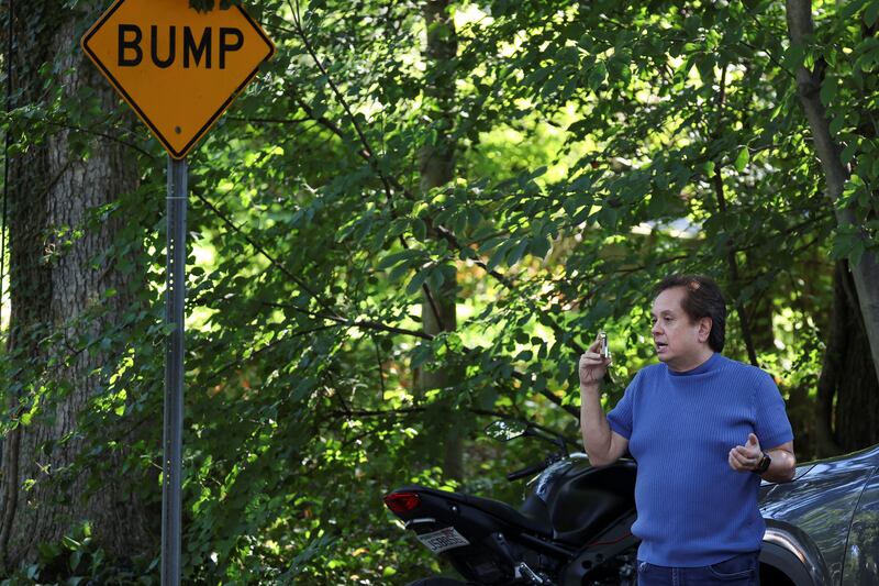 George Conway live streams on his phone outside the home of the former White House national security adviser John Bolton as it is searched by FBI members, in Bethesda, Maryland, Aug. 22, 2025.