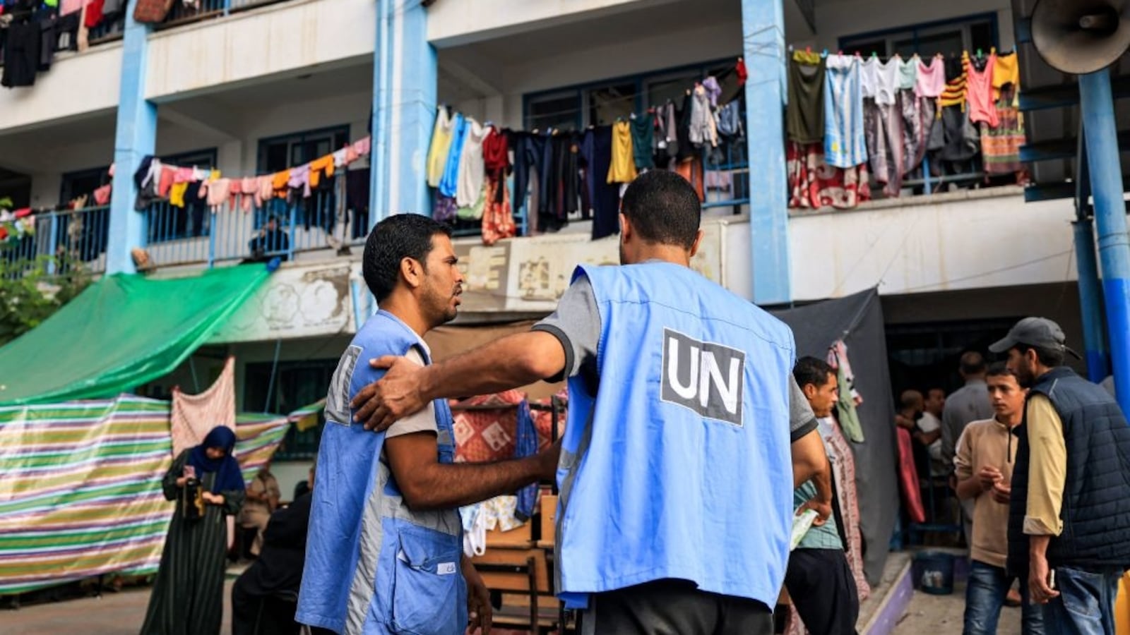 Workers of the UNRWA) agency talk together in the playground of an UNRWA-run school that has been converted into a shelter for displaced Palestinians in Khan Yunis in the southern Gaza Strip on October 25, 2023.