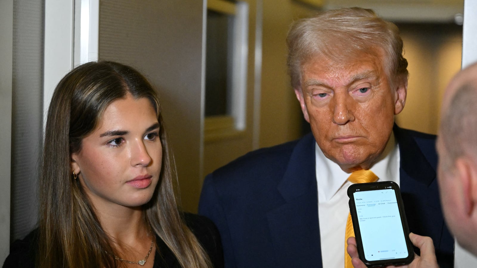 US President Donald Trump (C) listens to reporters as his granddaughter Kai Madison Trump looks on on board Air Force One while flying from Miami to Palm Beach on April 13, 2025, after watching the featherweight fight between Australian fighter Alexander Volkanovski and Brazilian fighter Diego Lopes (R) during UFC 314 at the Kaseya Center in Miami. (Photo by Mandel NGAN / AFP via Getty Images)