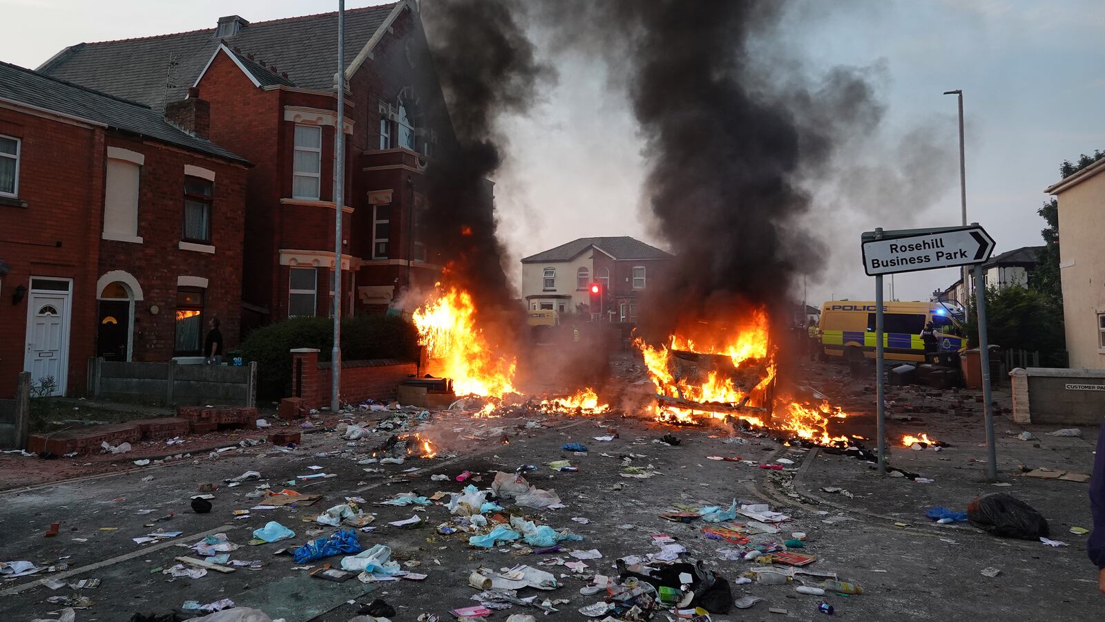 Riot police hold back protesters near a burning police vehicle after disorder broke out on July 30, 2024 in Southport, England.