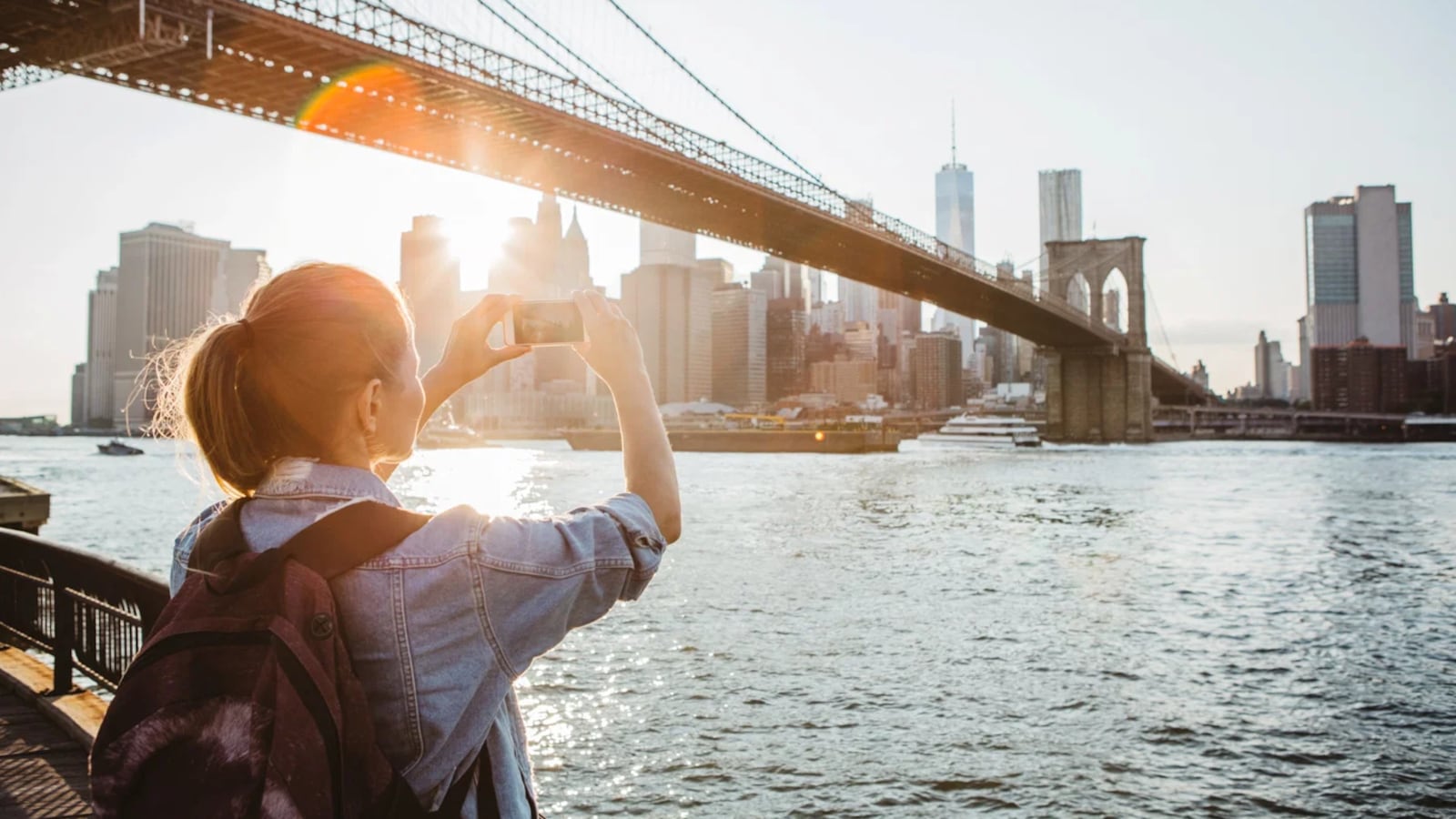 Woman taking a photo of the New York City skyline with her phone.