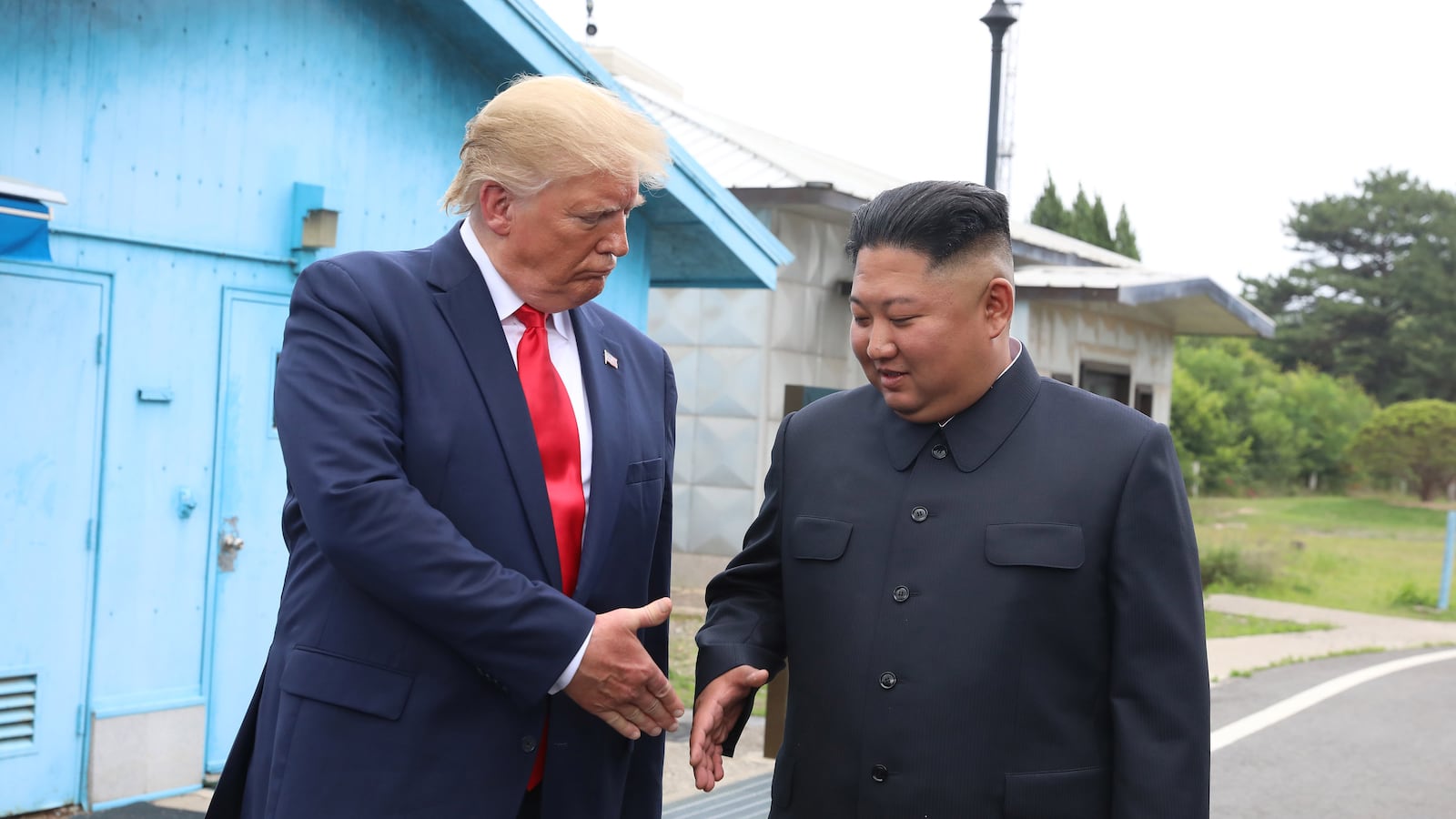 Donald Trump and Kim Jong-Un shake hands.