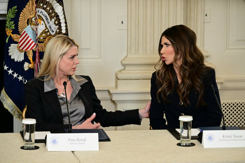 US Attorney General Pam Bondi (L) speaks with Homeland Security Secretary Kristi Noem before President Donald Trump (C) makes an announcement in the State Dining Room of the White House on October 23, 2025 in Washington, DC. (Photo by Jim WATSON / AFP) (Photo by JIM WATSON/AFP via Getty Images)
