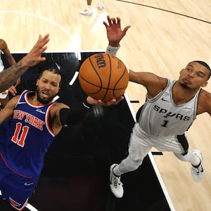 Jalen Brunson of the New York Knicks shoots the ball between Julian Champagnie and Victor Wembanyama